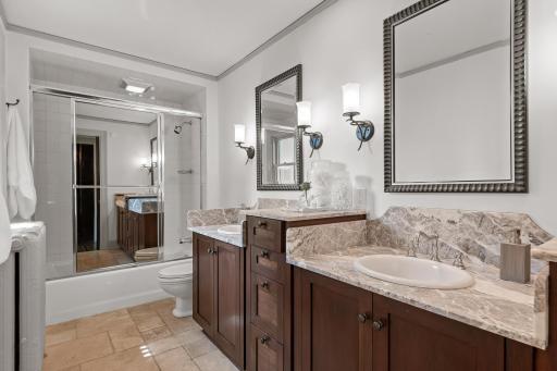 Beautiful owner's bathroom with stone finishes, dual sinks, and tiled tub/shower combo.