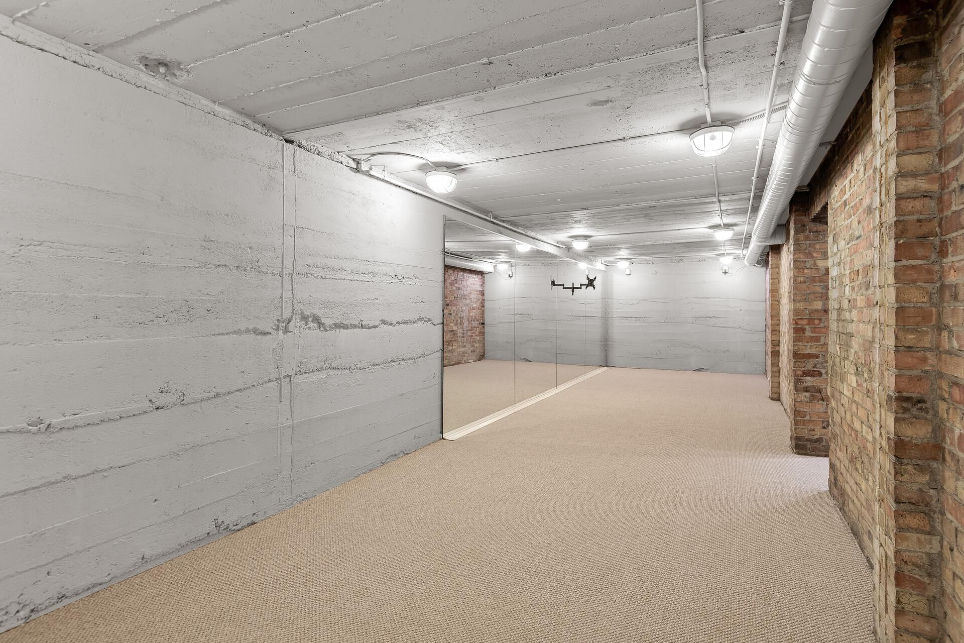 Enormous industrial style workout room with mirrored wall and brick accents.