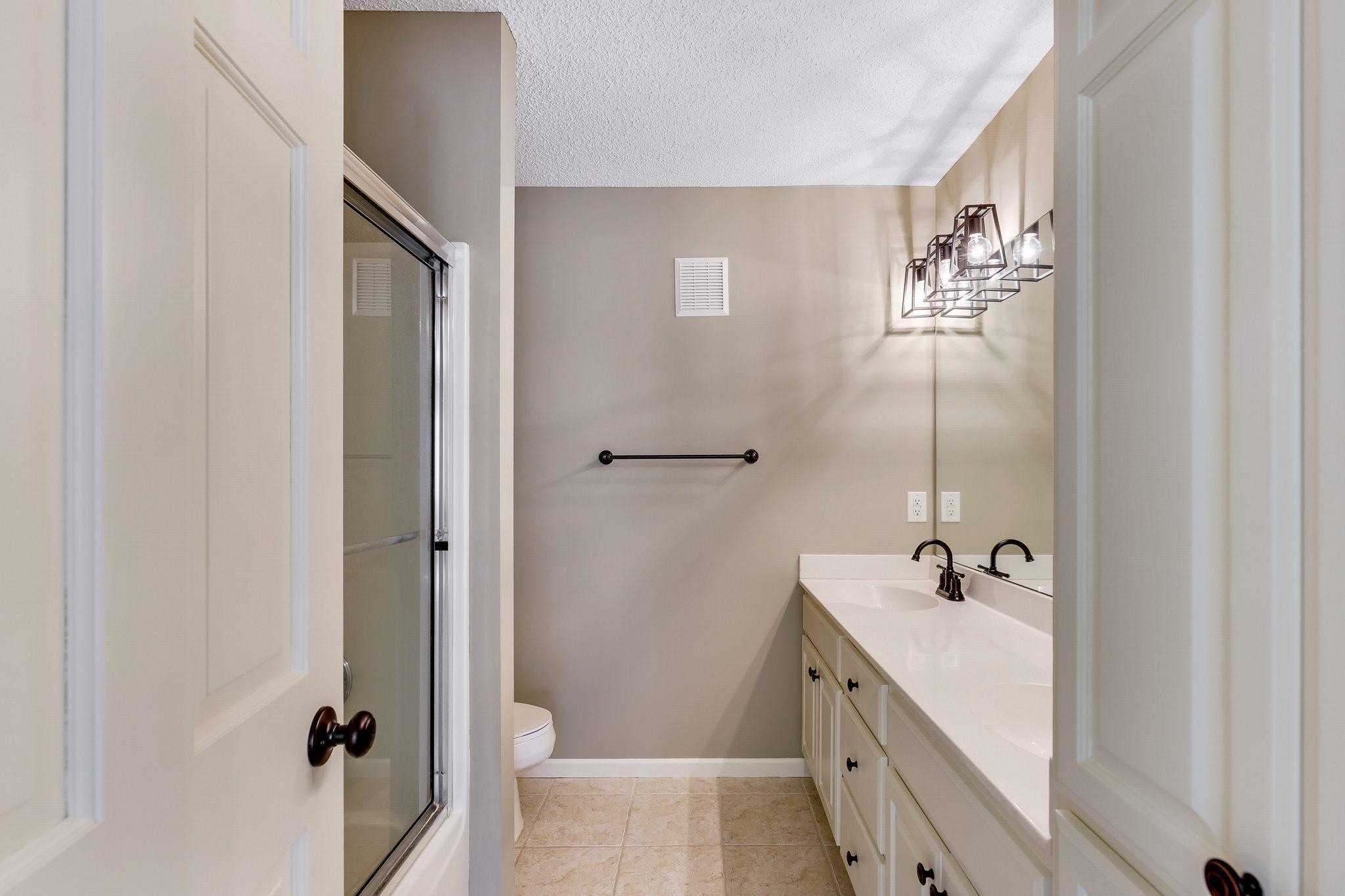 Upper level Full Bathroom features enameled vanity cabinet and linen closet, dual sinks glass shower doors and ceramic tile flooring