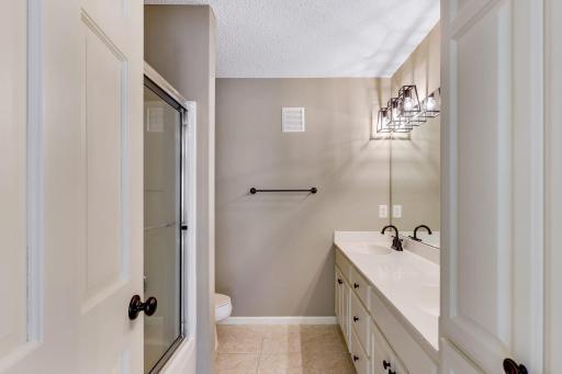 Upper level Full Bathroom features enameled vanity cabinet and linen closet, dual sinks glass shower doors and ceramic tile flooring