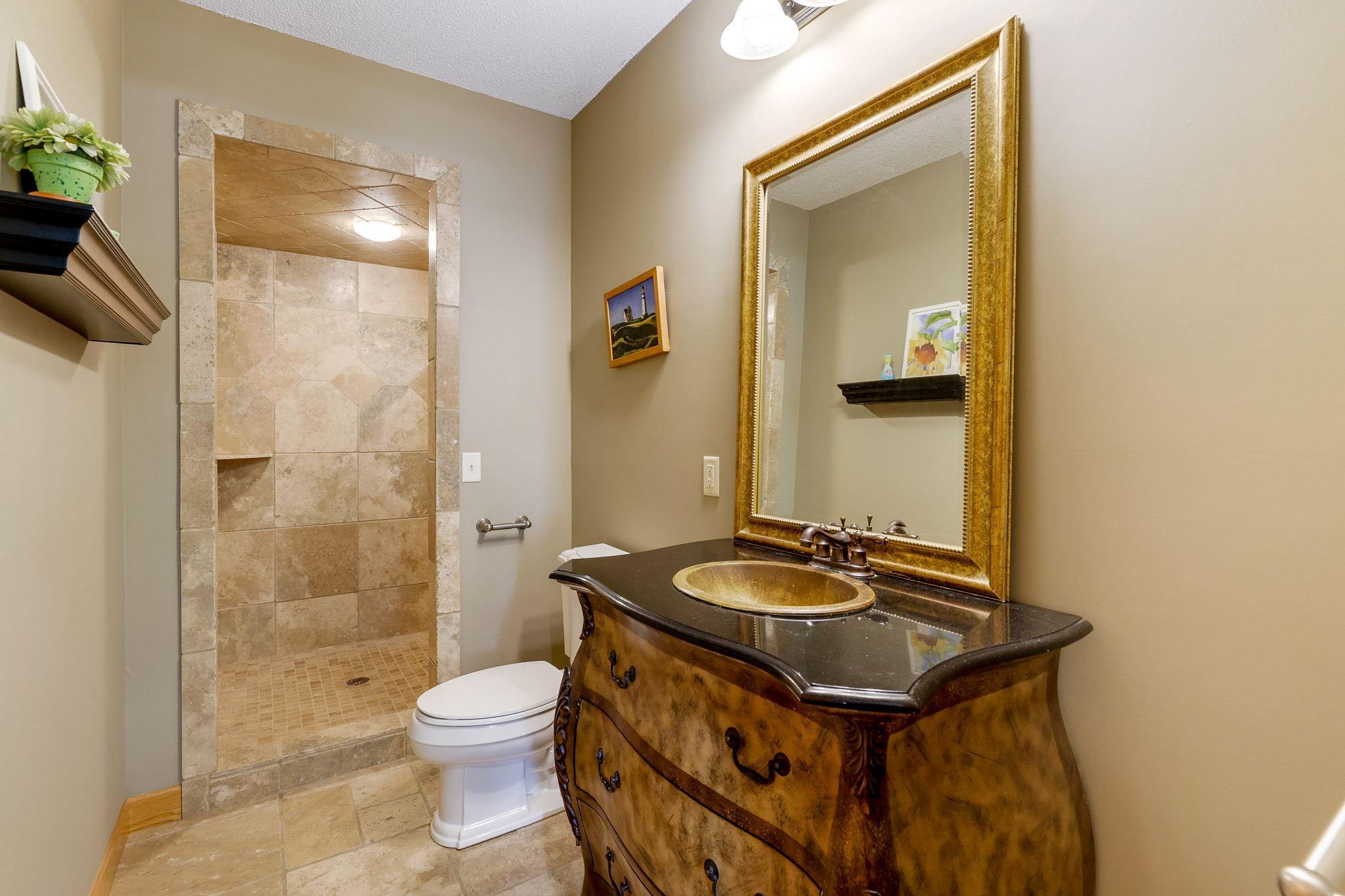 Lower level Bathroom offers a large walk-in shower with travertine tile surround