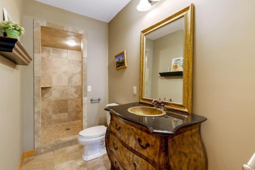 Lower level Bathroom offers a large walk-in shower with travertine tile surround