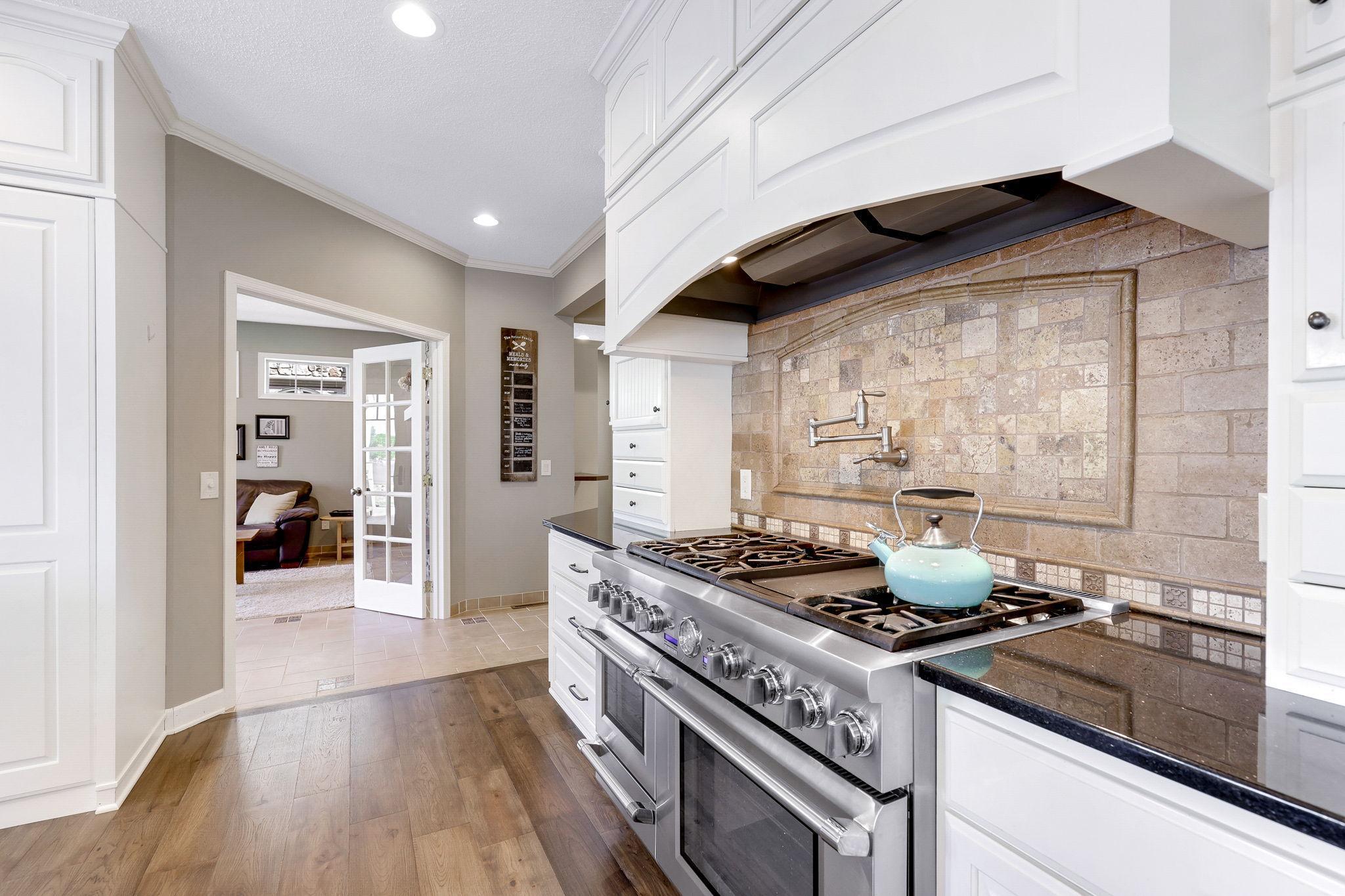 Pot filler faucet installed over the Thermador 48" gas range w/ cabinet paneled Vent-A-Hood