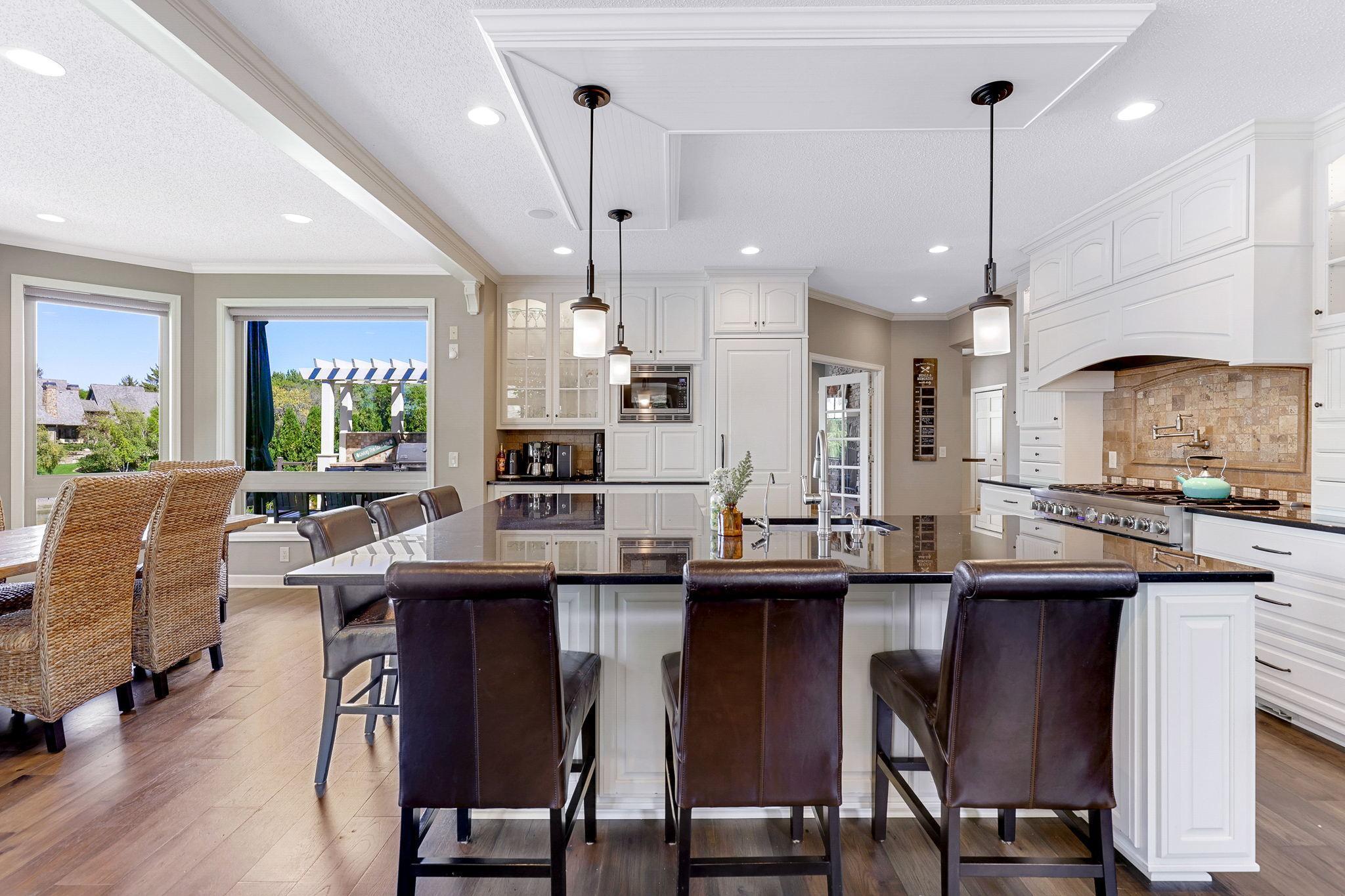 Custom enameled cabinetry features glass doors w/ interior accent lighting, raised panel doors, roll-out storage, full height uppers and grand size “eat-in” center island