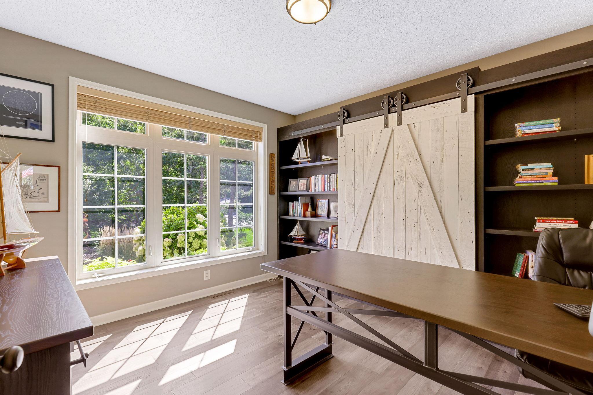 Full glass French doors access this main level office. Take note of the custom built bookcase and handcrafted barndoors, function and beauty!