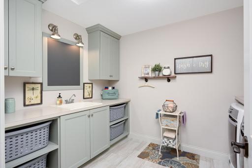Spacious second floor laundry with sink and storage cabinets