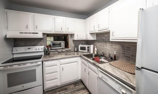 Kitchen is spacious and has tons of cabinet space. Range and kitchen light fixture are newer! Notice the pass through window into the dining room.