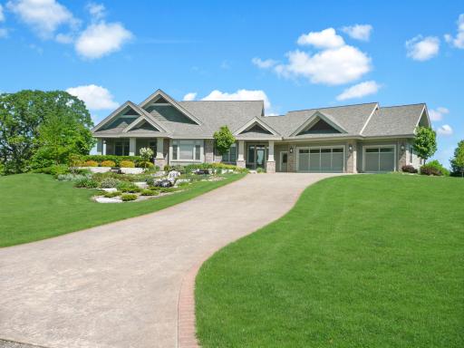 Summer view of home with stamped concrete driveway & landscaping