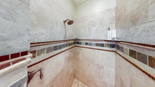 Large walk-in shower with Kohler hardware including a traditional shower head, and a separate rain shower head