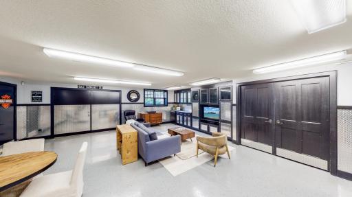 Large finished storage room thru black double doors with commercial air compressor with lines running up to overhead garage