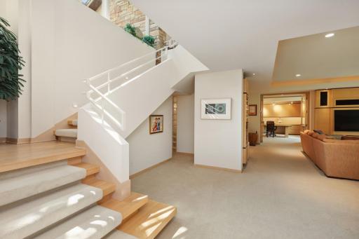 The staircase dressed in maple hardwood steps and carpet runner is inconspicuous as it sinks into a palette of pale white with emphasis on bringing in the outdoor views and waterfall light which canvases the staircase wall.