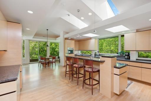 The kitchen is dreamy and boasts top-of-the-line appliances, maple cabinetry and flooring, granite countertops on both the perimeter and center island, and over and under cabinet windows to deliver the outdoors inside.