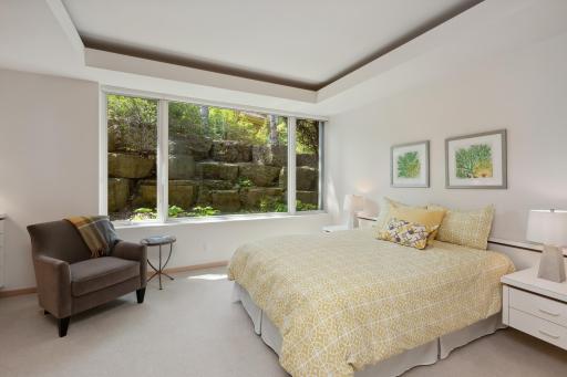 Landscaping outside the large picture window in this bedroom is extraordinary and creates a border of privacy for this suite. Enjoy the custom built-in dresser and recessed lighting.