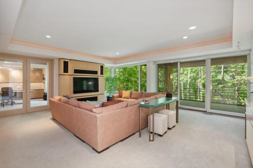 The family room is spacious and hosts both a large built-in screen tv into an entertainment center, large area for entertainment, mood lighting at custom ceiling soffit, built-in console table for storage, and walkout to a lovely covered patio.