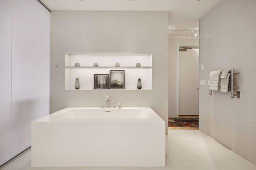 Owner's soaking tub with an art display shelf above.