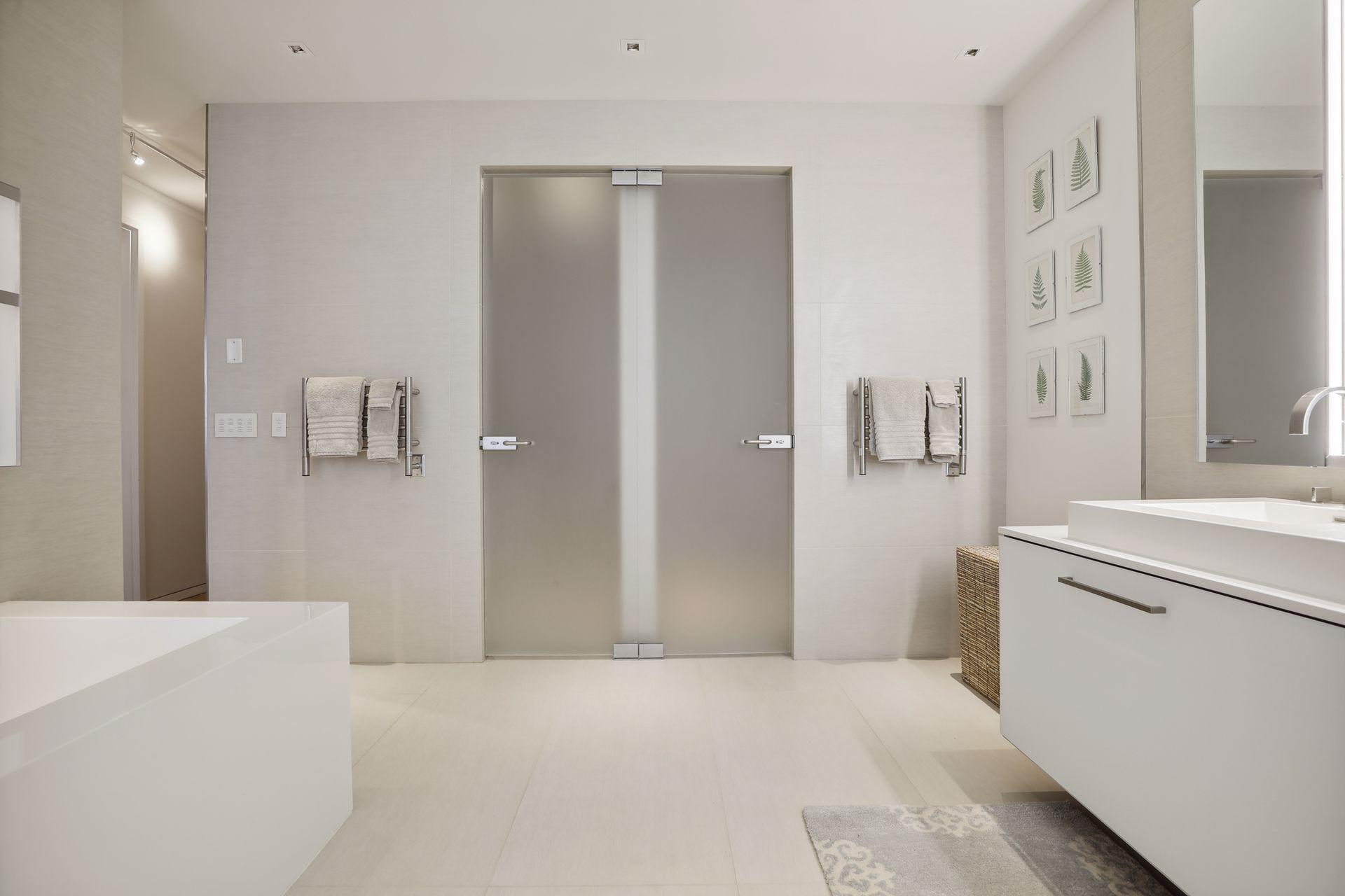Owner's bath with heated towel racks, custom lighting, and a large soaking tub. Etched glass doors lead to a water closet and a large walk-in rain shower.