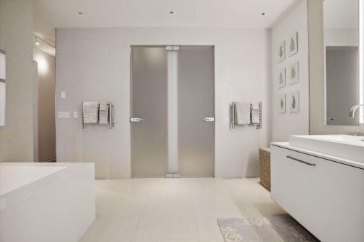 Owner's bath with heated towel racks, custom lighting, and a large soaking tub. Etched glass doors lead to a water closet and a large walk-in rain shower.