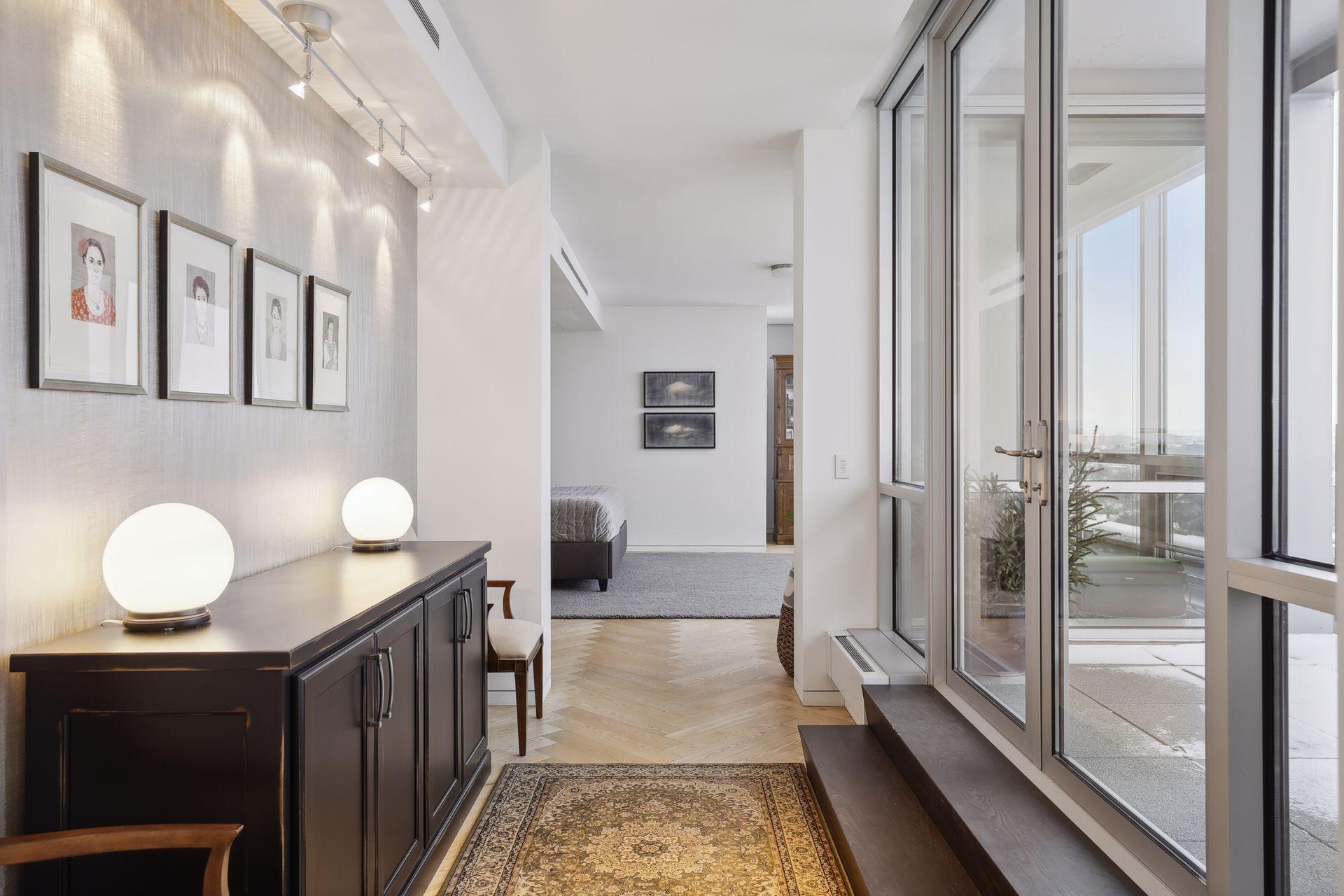 A wide hall leads from the living room into the main level bedroom suite which features solid black ask herringbone floors, a private terrace, walk-in closet with a large laundry room, and private bath designed for two.