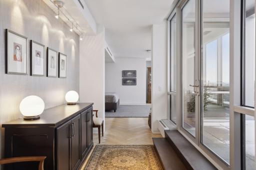A wide hall leads from the living room into the main level bedroom suite which features solid black ask herringbone floors, a private terrace, walk-in closet with a large laundry room, and private bath designed for two.