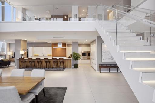 The illuminated floating staircase leads to upper level living areas, a guest bedroom and guest bath, and the primary bedroom suite as well as two additional terraces.