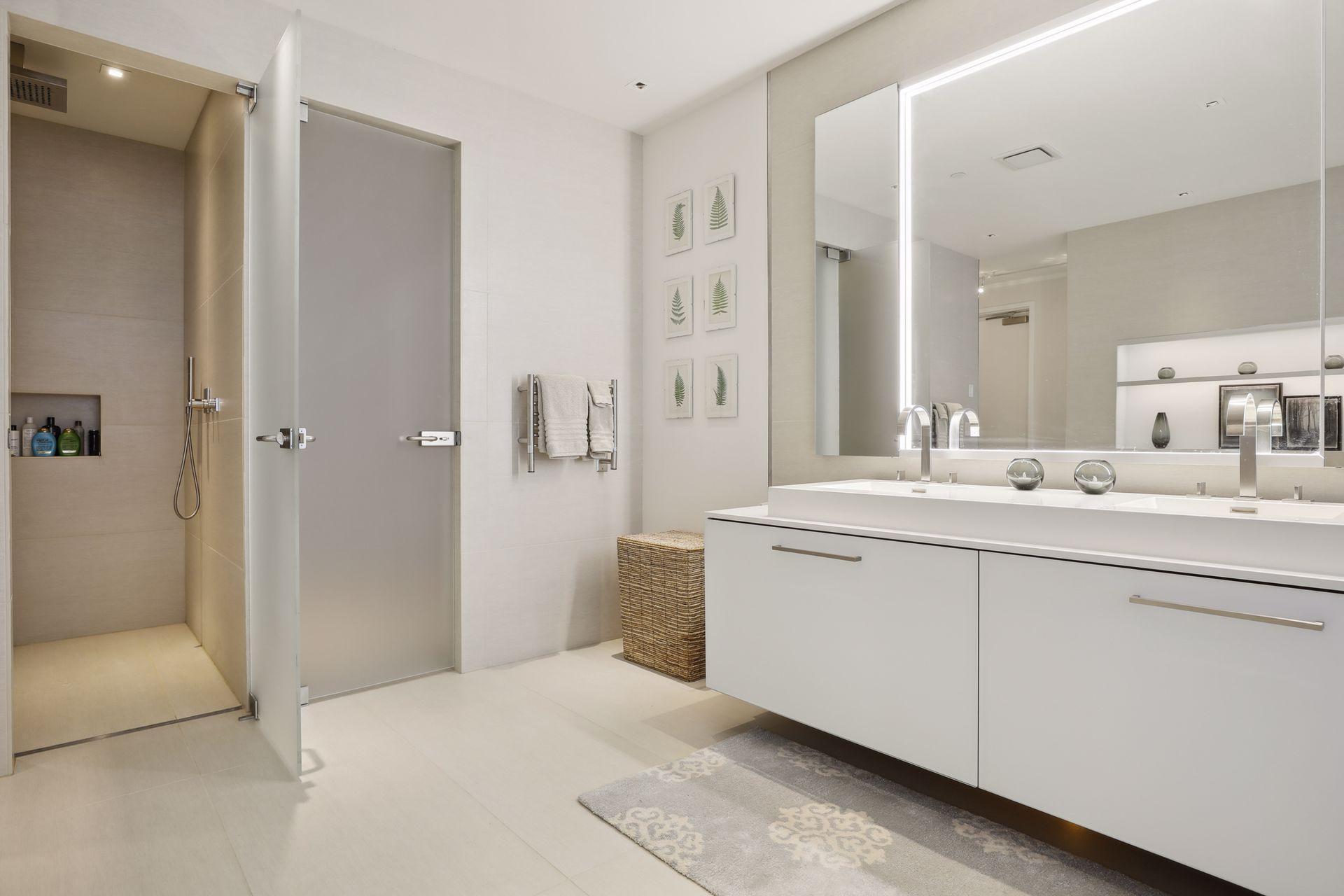 The luxurious spa-like owner's suite bath includes tile floors, a double vanity, a separate soaking tub with art display shelving above, a large walk in shower with built-in bench and etched glass door, and a water closet with an etched glass door.