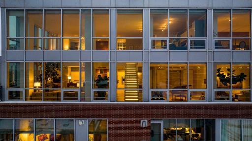 An aerial view of the east facing windows showcase the illuminated floating staircase to the upper level living spaces.