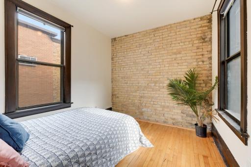 The bedroom features an exposed brick wall.