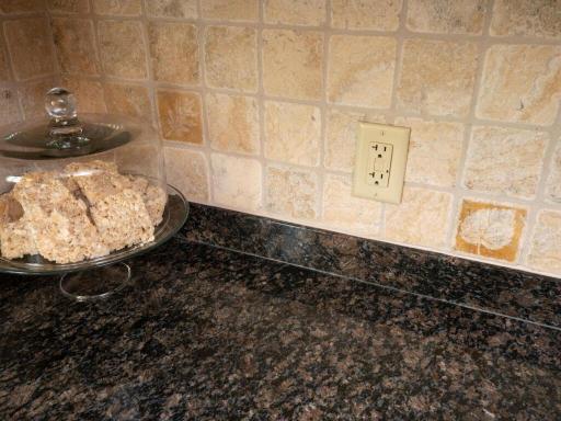Granite countertops and ceramic tile backsplash in the kitchen.