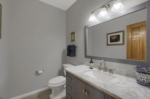 Updated main floor powder room with large vanity featuring a marble top and soft close doors.