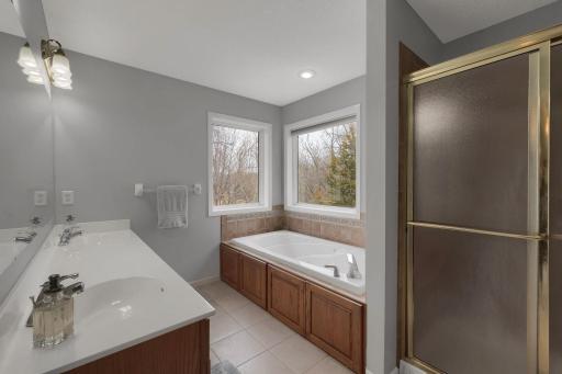 Primary bathroom with double vanity, jacuzzi tub, separate shower, and views of the lake.