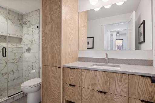 The upper level hall Bathroom offers extensive cabinetry with a linen cabinet and large tiled shower.