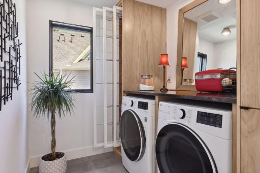 Located on the upper level is one of two laundry rooms. This space features an LG front load washer and dryer, granite folding counter and pull-out drying racks.