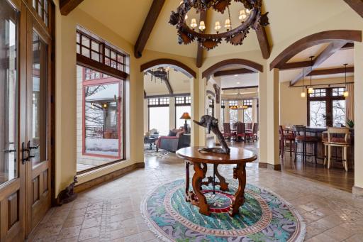 The front door opens to reveal the grand foyer with an exquisite custom-carved chandelier.