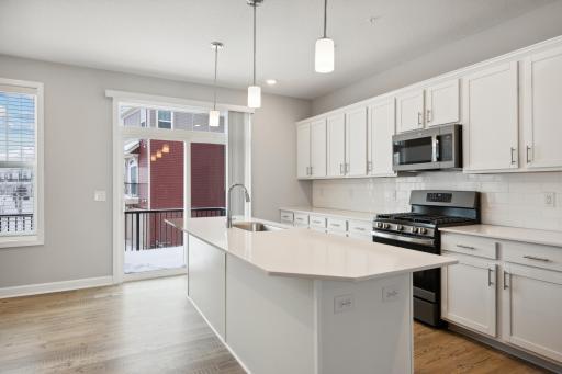 Beautiful kitchen featuring white cabinets, quartz countertops, gas range and ceramic backsplash. Photos are not of actual home. Actual home will be similar. Some colors and features may vary.