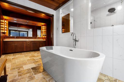 The primary bathroom features a spacious double vanity with built in storage, a separate soaking tub, a large walk-in shower and leads into the generous walk-in closet.