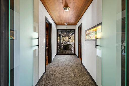 The primary wing is separated by glass doors leading to the primary suite and a bedroom or office space.