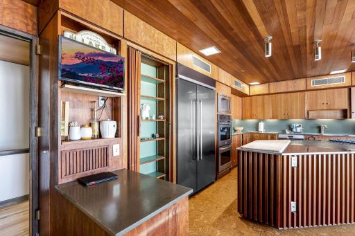 The eat-in kitchen features a walk-in pantry, indoor grill with ventilation, stone fireplace, double wall ovens, stainless counter tops and appliances, cork flooring, custom cabinetry and a 5 burner, gas cooktop.