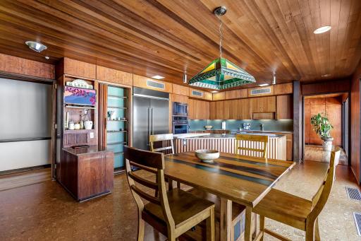 The eat-in kitchen features a walk-in pantry, indoor grill with ventilation, stone fireplace, double wall ovens, stainless counter tops and appliances, cork flooring, custom cabinetry and a 5 burner, gas cooktop.