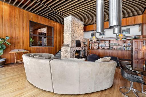 Enjoy stunning views from the living room featuring floor to ceiling windows, custom Frank Lloyd Wright replica lighting, custom Bollenbach stainless steel lighting, a sunk-in seating area with built-ins, 14-foot-tall ceilings and Teak walls.