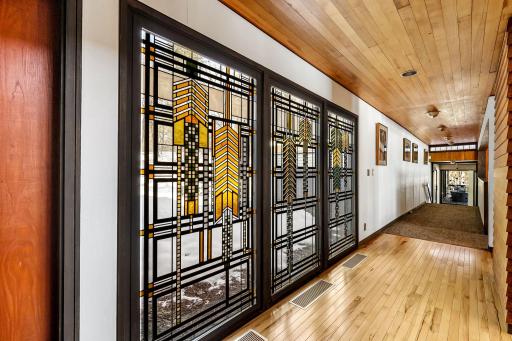 The grand foyer leads into the spacious home featuring white walls for fine art lighting, spacious hallways and doorways, exquisite stained glass windows and Frank Lloyd Wright inspired details throughout.