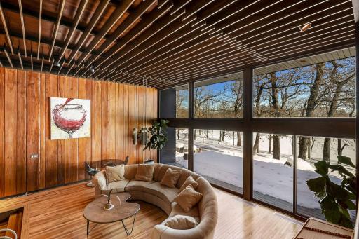 Enjoy stunning views from the living room featuring floor to ceiling windows, custom Frank Lloyd Wright replica lighting, custom Bollenbach stainless steel lighting, a sunk-in seating area with built-ins, 14-foot-tall ceilings and Teak walls.
