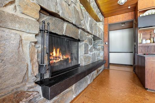 The eat-in kitchen features a walk-in pantry, indoor grill with ventilation, stone fireplace, double wall ovens, stainless counter tops and appliances, cork flooring, custom cabinetry and a 5 burner, gas cooktop.