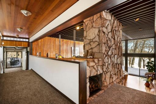 Enjoy stunning views from the living room featuring floor to ceiling windows, custom Frank Lloyd Wright replica lighting, custom Bollenbach stainless steel lighting, a sunk-in seating area with built-ins, 14-foot-tall ceilings and Teak walls.