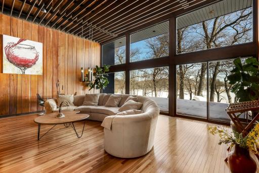 Enjoy stunning views from the living room featuring floor to ceiling windows, custom Frank Lloyd Wright replica lighting, custom Bollenbach stainless steel lighting, a sunk-in seating area with built-ins, 14-foot-tall ceilings and Teak walls.