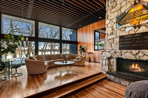 Enjoy stunning views from the living room featuring floor to ceiling windows, custom Frank Lloyd Wright replica lighting, custom Bollenbach stainless steel lighting, a sunk-in seating area with built-ins, 14-foot-tall ceilings and Teak walls.