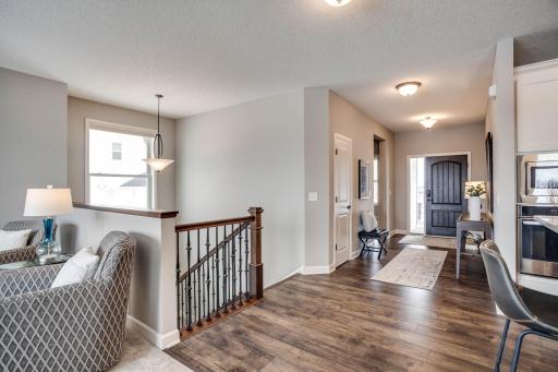 An inviting welcome, the sunny foyer is spacious and opens easily to the main level gathering areas. Also note the huge window, rich millwork and wrought-iron balusters along the staircase leading to the walk-out lower level.