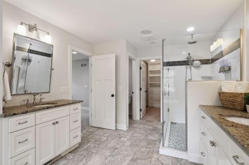 The primary bathroom features dual vanities, a free-standing bathtub, glass surround custom shower, and walk-in closet.
