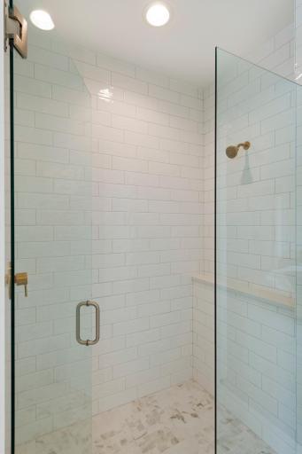 All tile shower with frameless glass and a product ledge