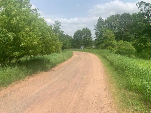 Land to the left and more land and lake forward and across the road.