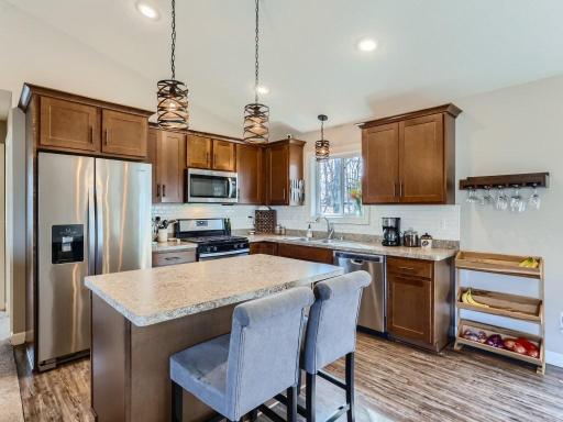 The kitchen boasts maple cabinetry, soft close doors, stainless steel appliances, and an island with seating+storage.